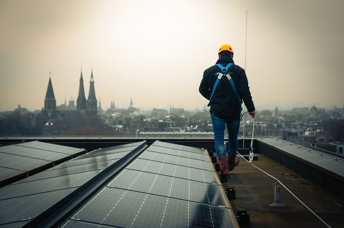 construction worker walking on roof edge connected to a horizontal lifeline system