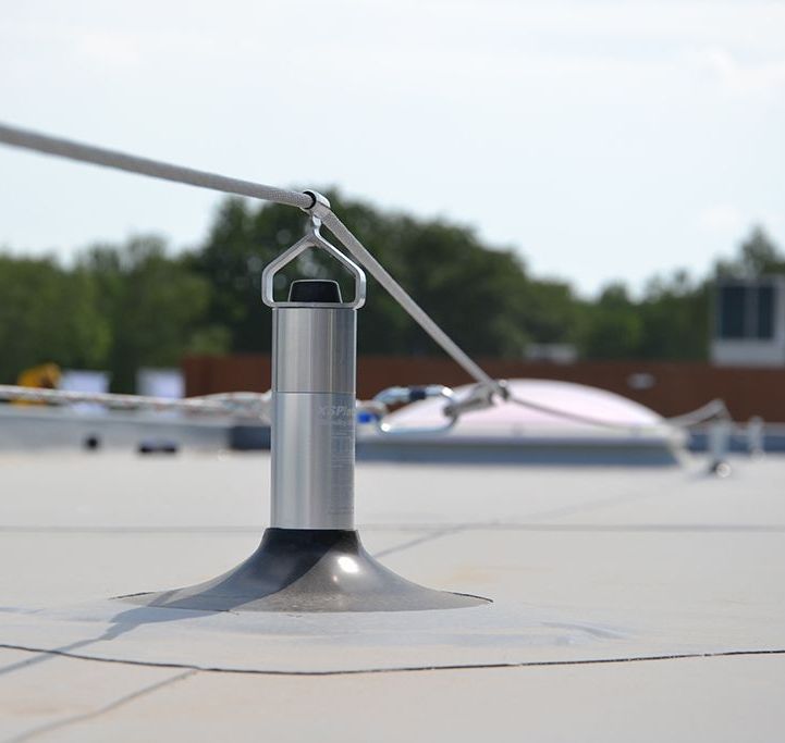 A metal pole with a rope attached to it is on a roof.
