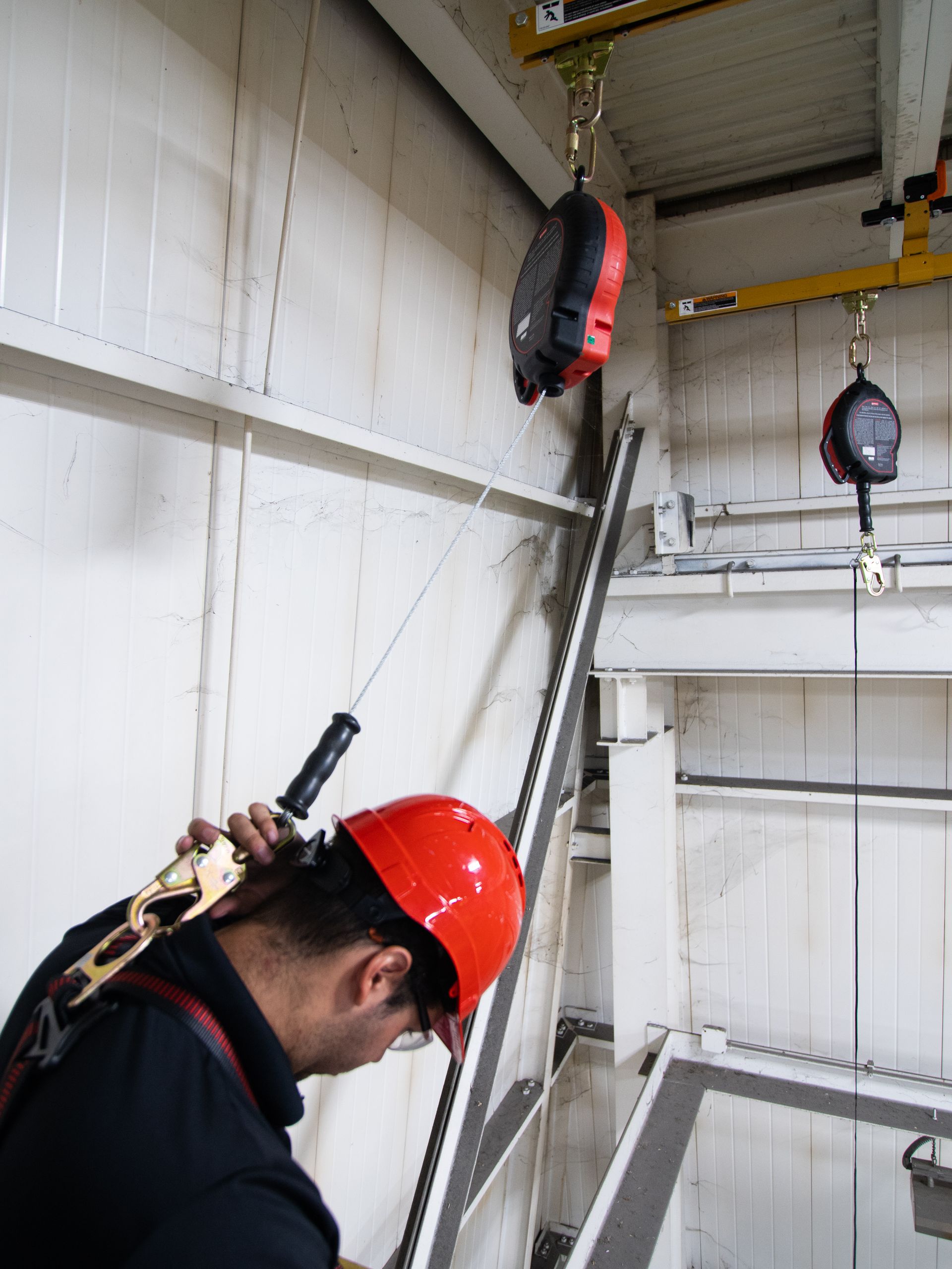 A man wearing a red hard hat is working on a crane