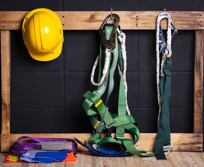 A yellow hard hat is hanging on a wooden frame.