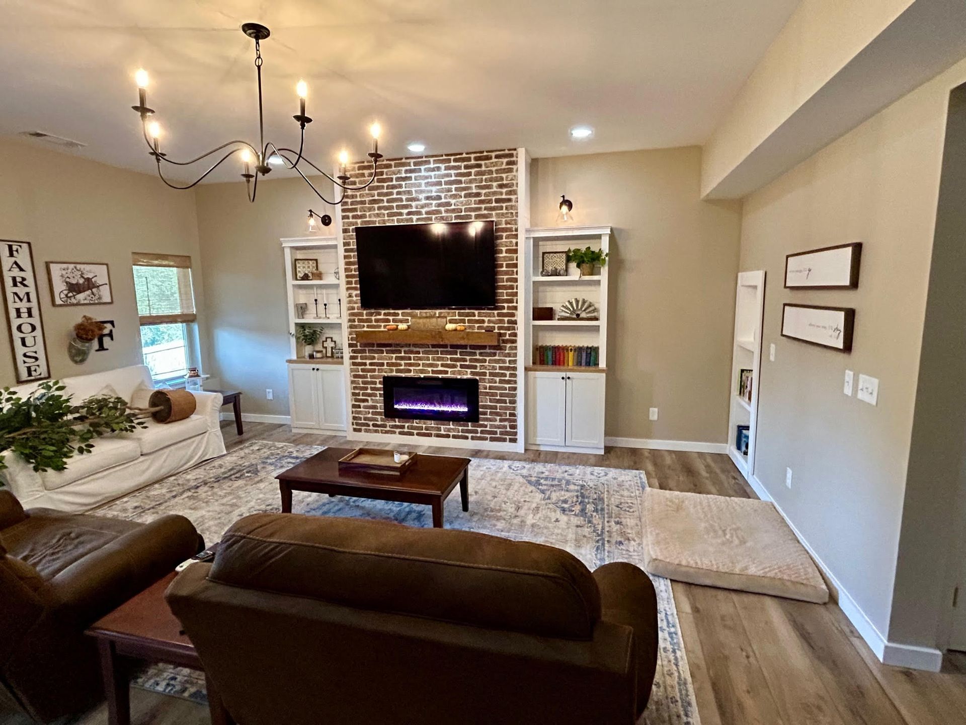 A living room with a fireplace , couch , chairs , coffee table and television.