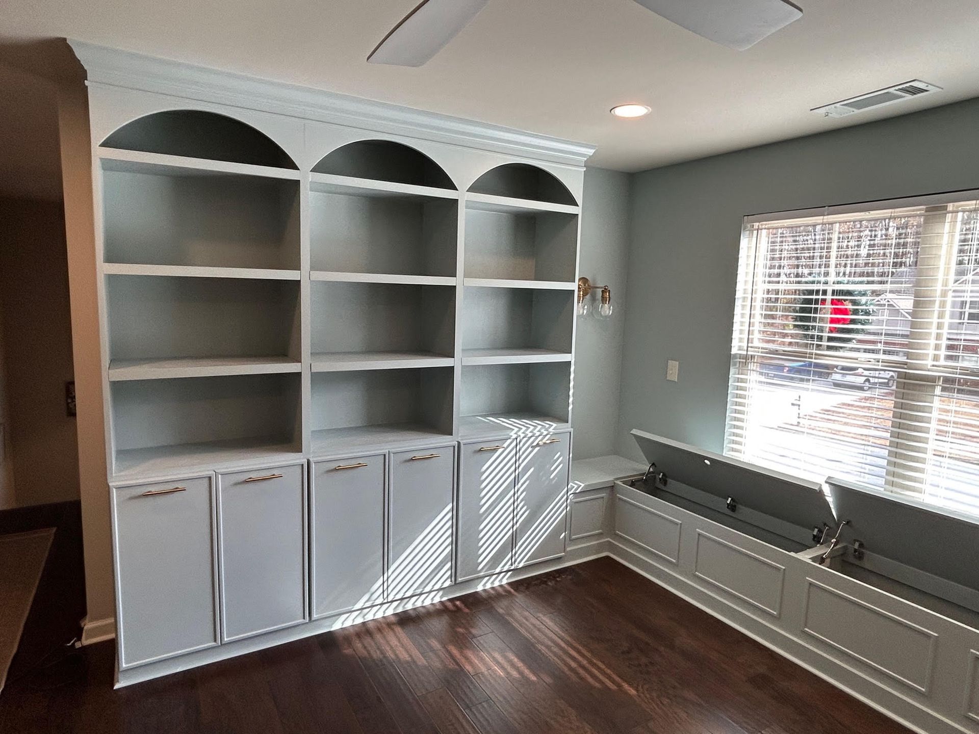 A room with a lot of shelves and a window.