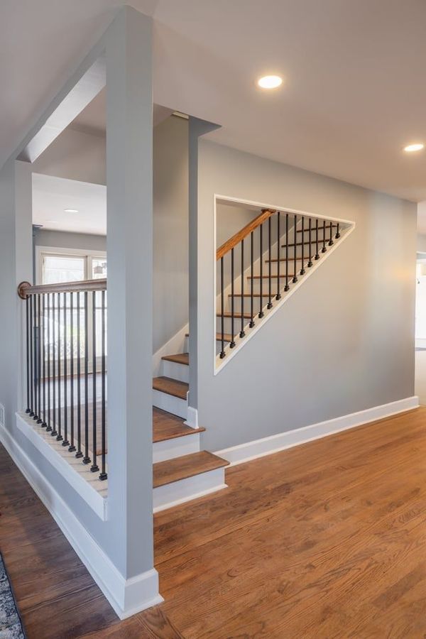 Interior staircase with gray walls, wood floors, and black metal railing in a bright hallway