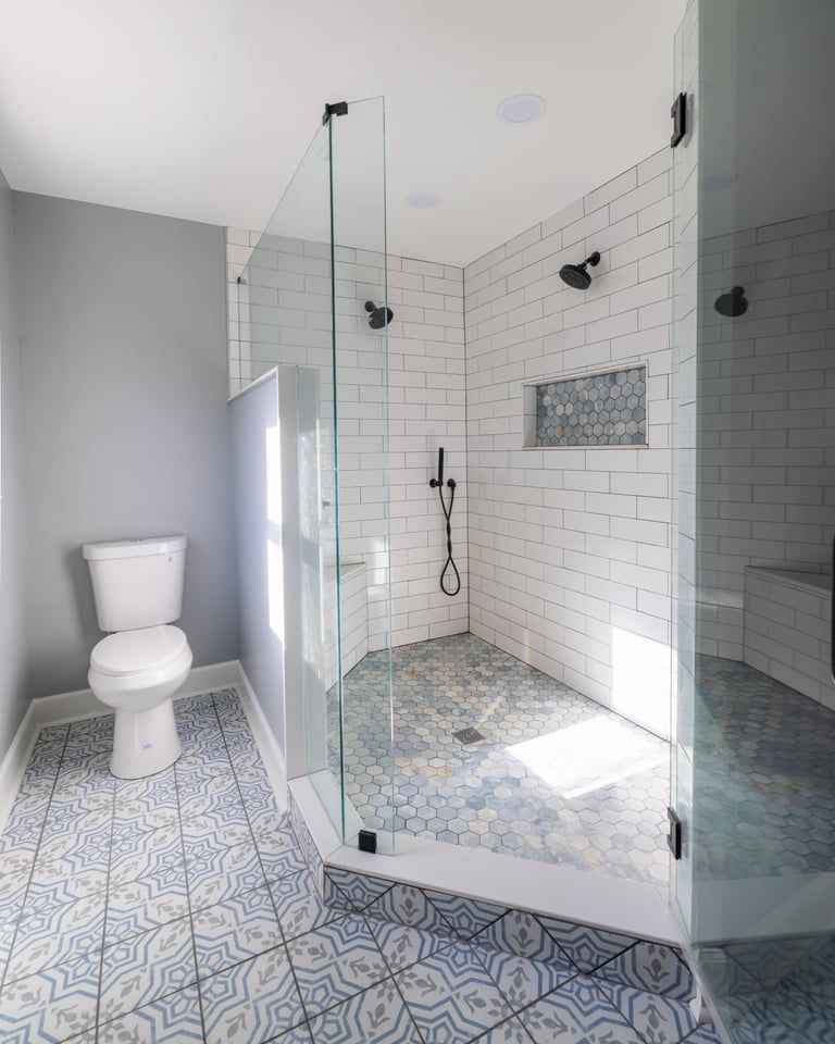 Modern bathroom with patterned tile floor, glass shower enclosure, and white toilet.