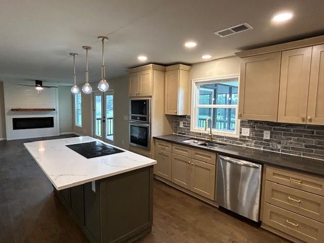 Modern kitchen with island, light wood cabinets, stainless appliances, and pendant lights