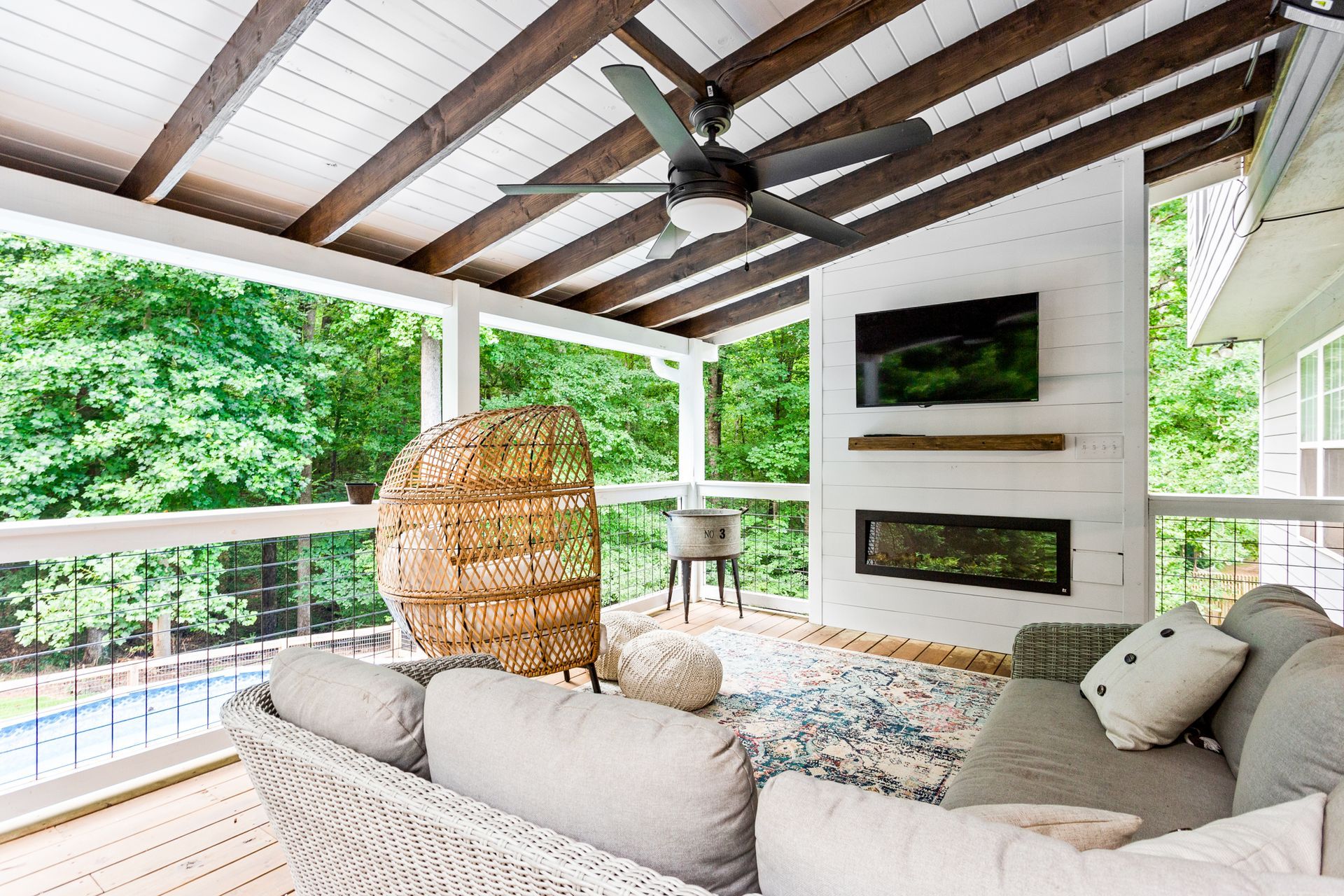 A living room with a couch , chair and ceiling fan on a porch.