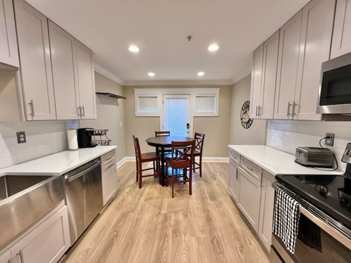 Kitchen with light-colored cabinets, stainless steel appliances, and a round dining table.