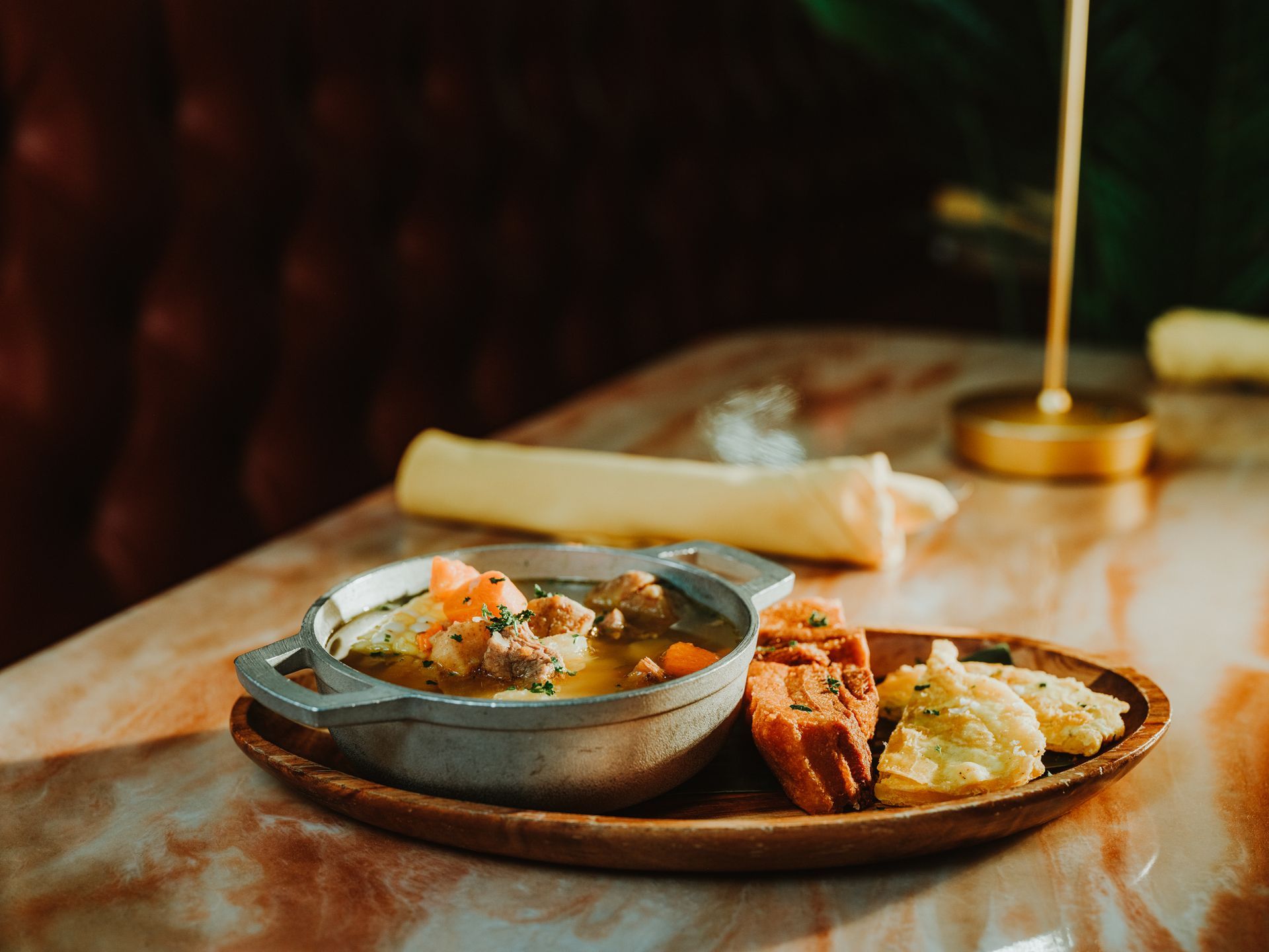Steaming bowl and plated appetizers on a wooden table with warm restaurant lighting