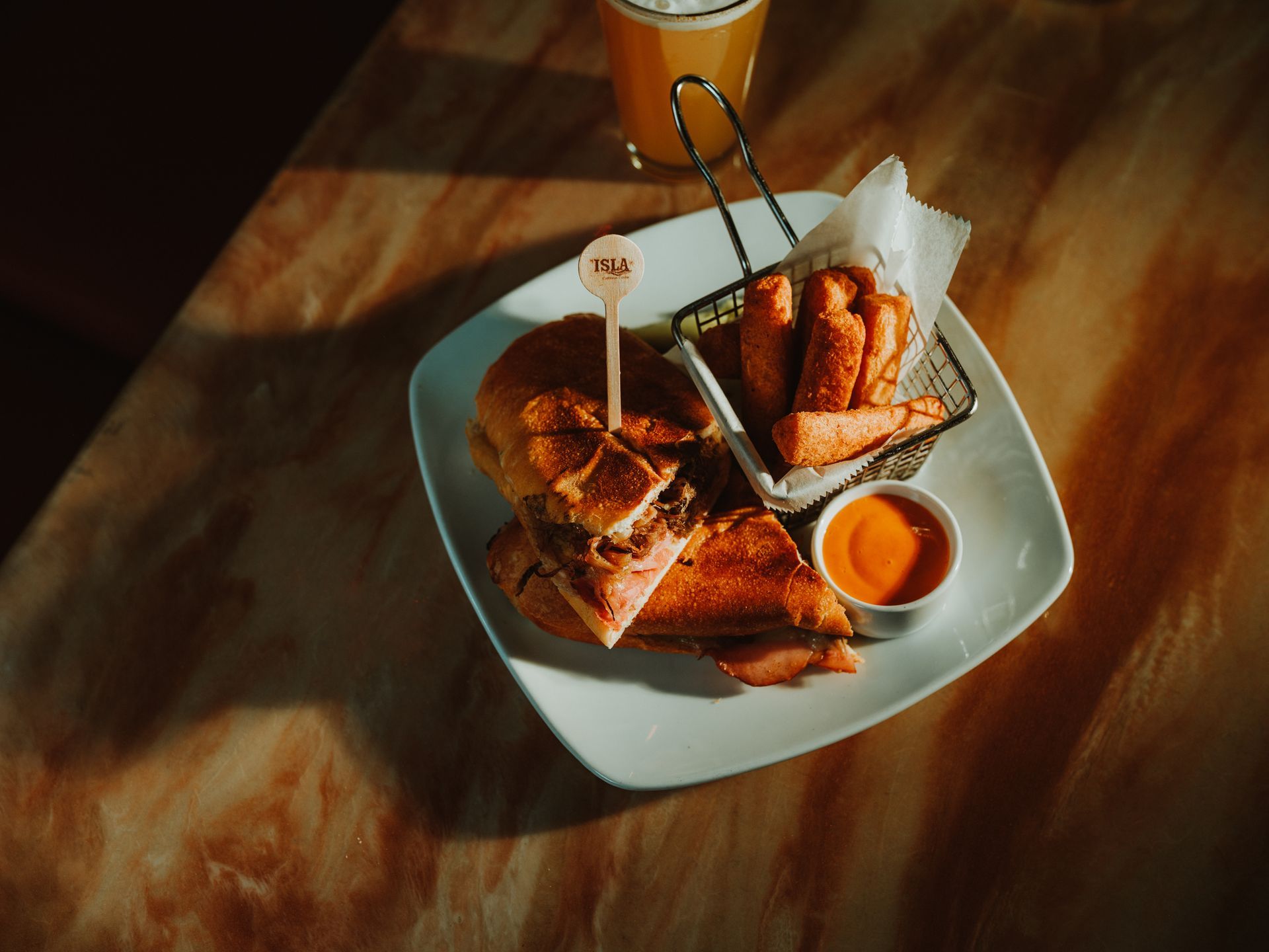 Chicken tenders and fries in a white basket on a table with dipping sauce and a drink