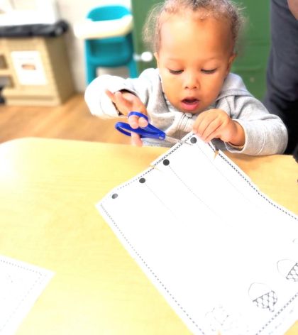 A baby is laughing in a play room with toys in the background.