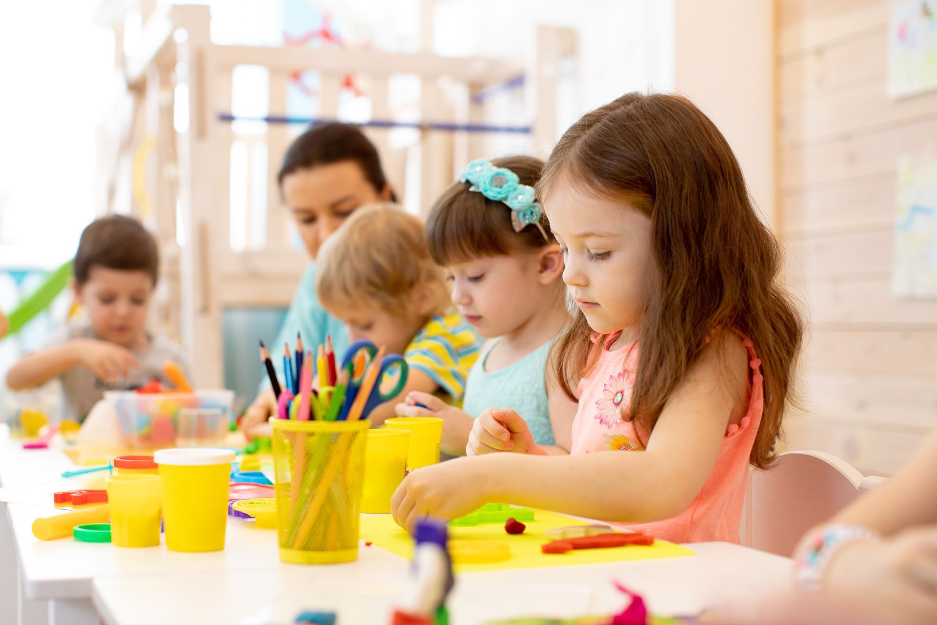 A group of children are sitting at a table playing with clay.