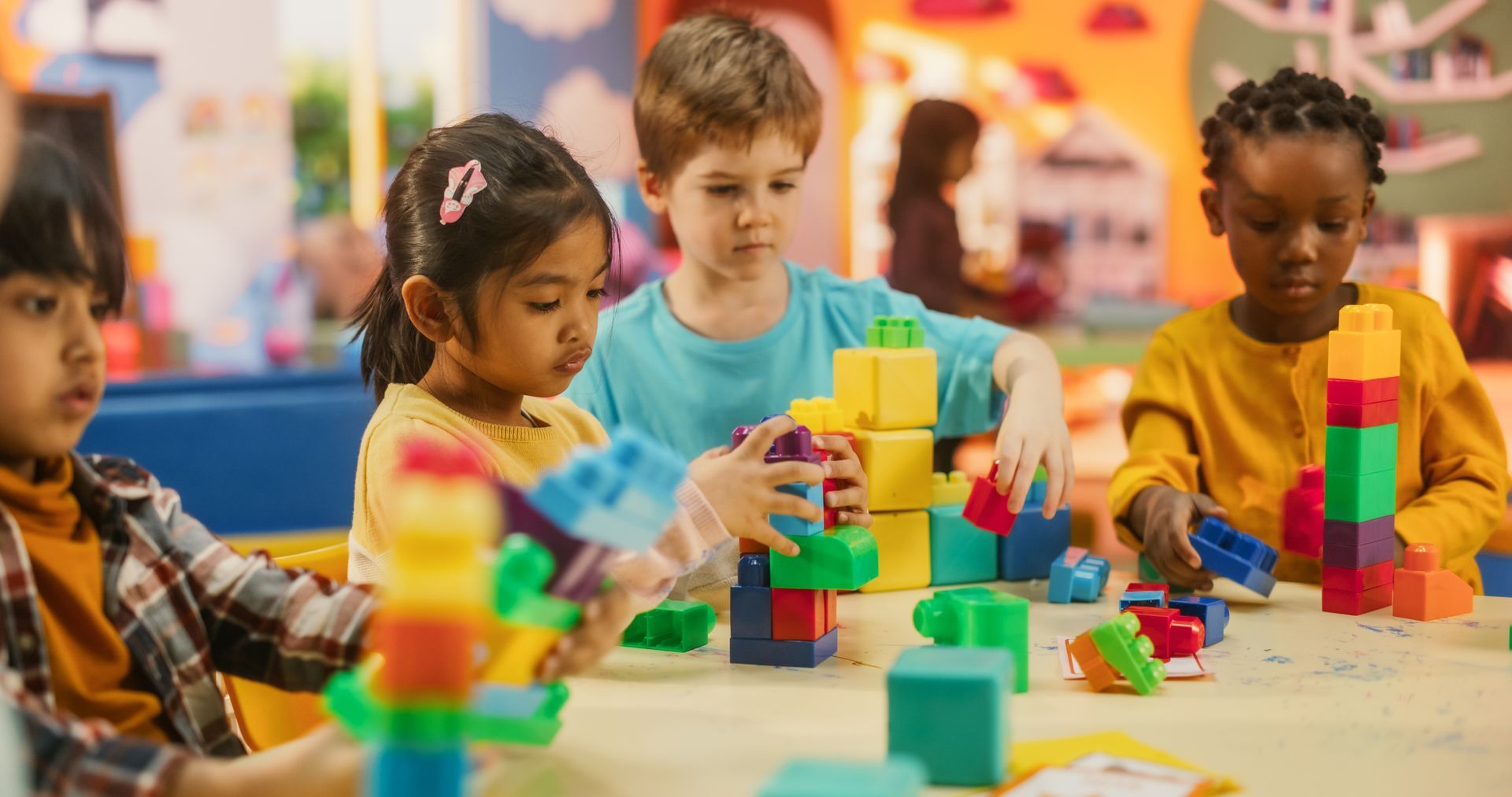 A group of children are playing with plastic blocks at a table.