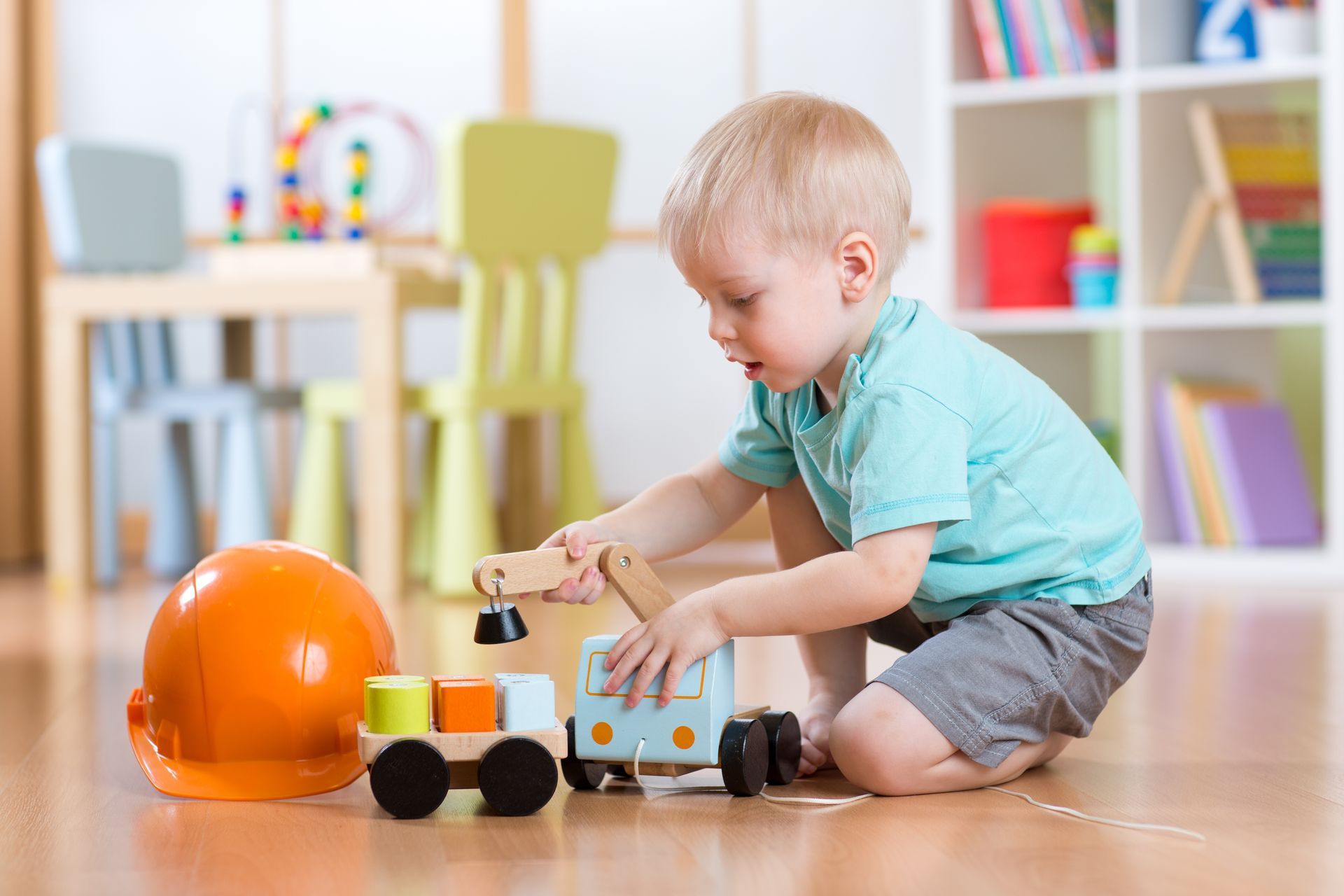 A little boy is sitting on the floor playing with a toy truck.