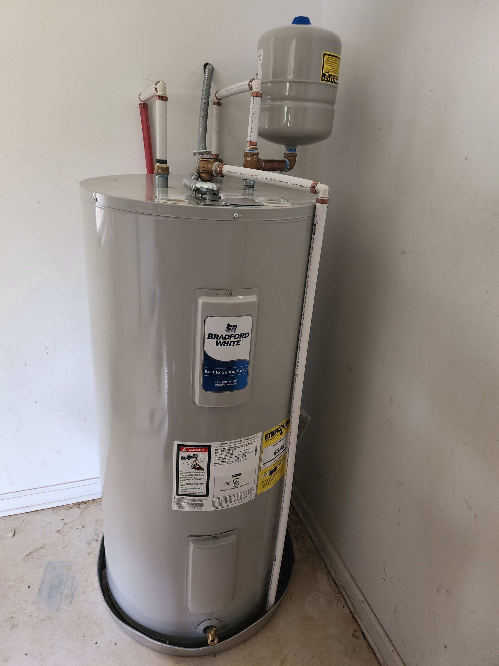 A tall, gray water heater with an expansion tank in a corner.
