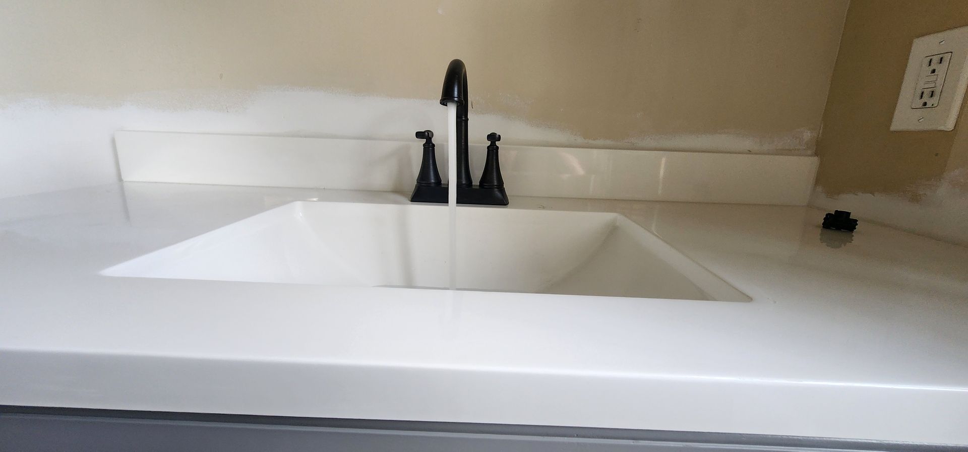 White bathroom sink with a black faucet.