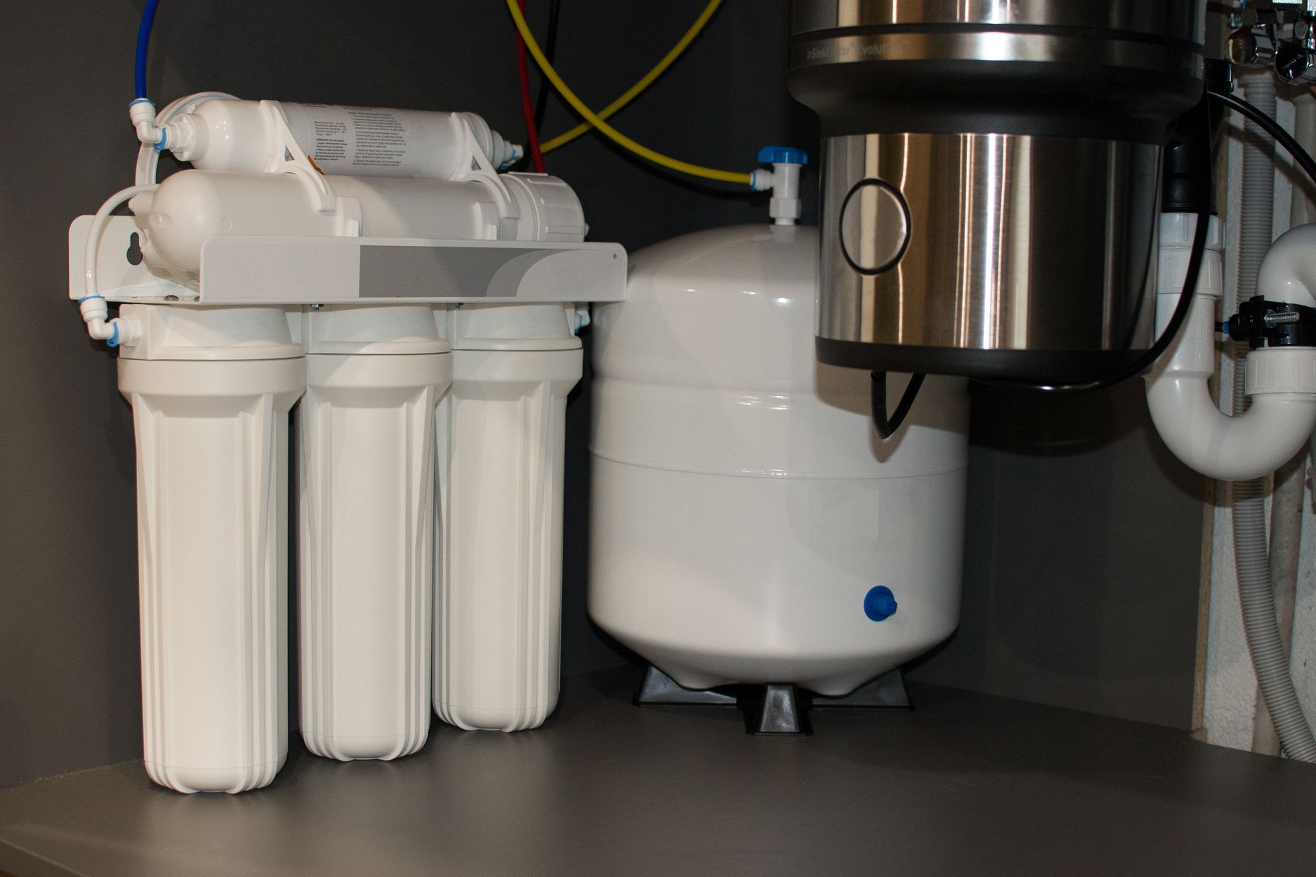 water treatment services cleveland nc Reverse osmosis water filtration system under a kitchen sink. White filters, tank, and plumbing.