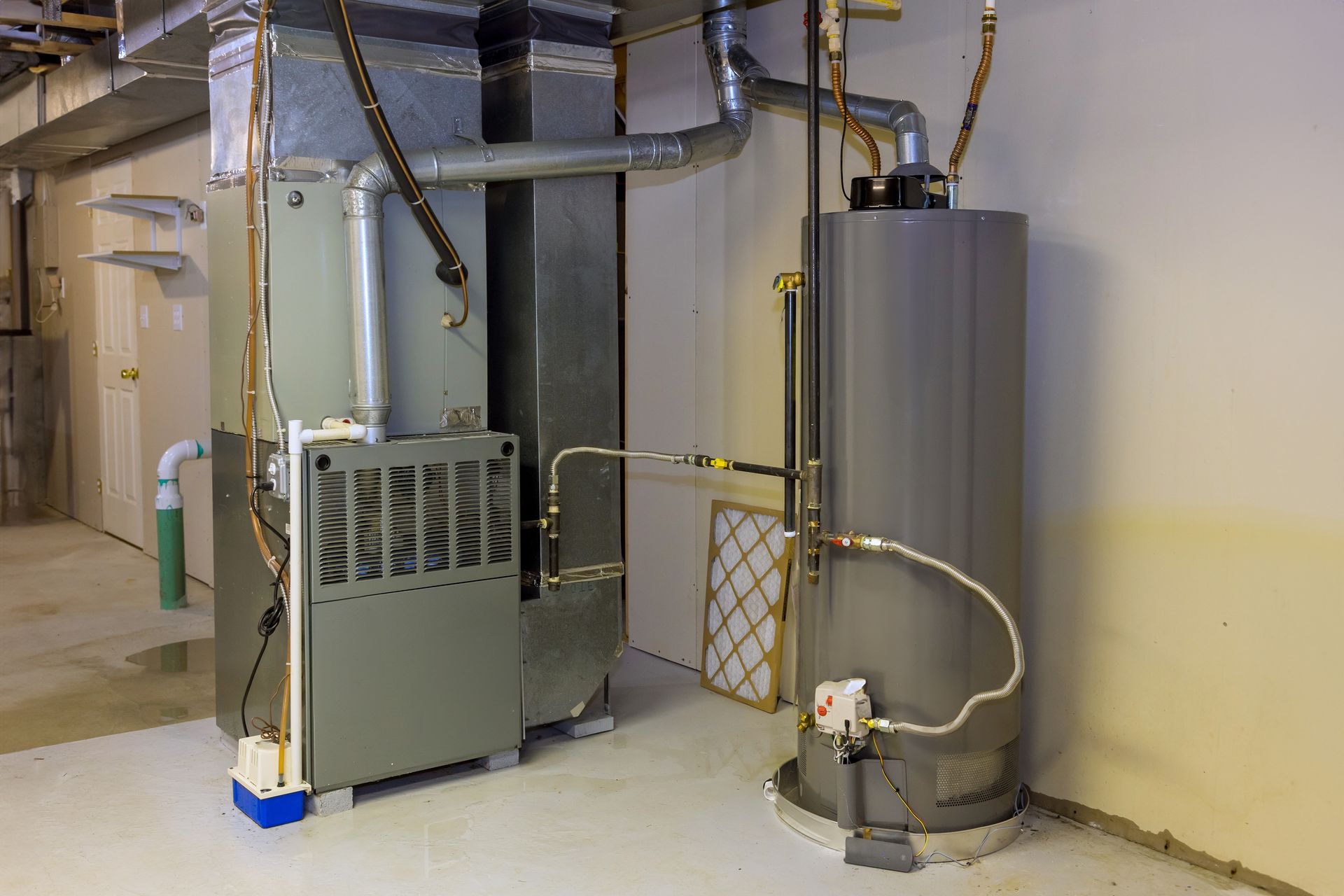 water heater installs cleveland nc Furnace and water heater in a utility room. Gray metal units, beige walls, and light floor.