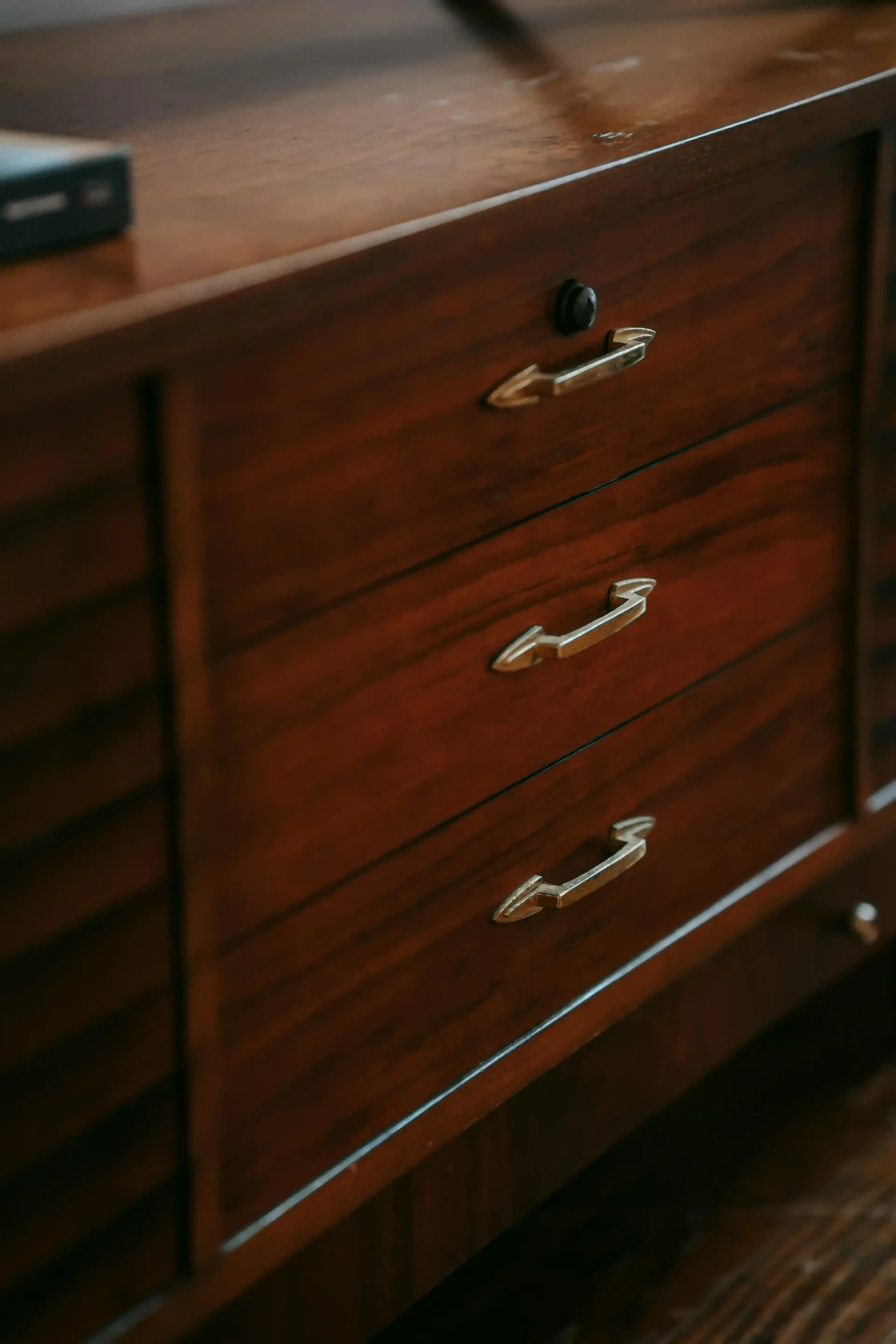 Wooden dresser with three drawers and gold handles.