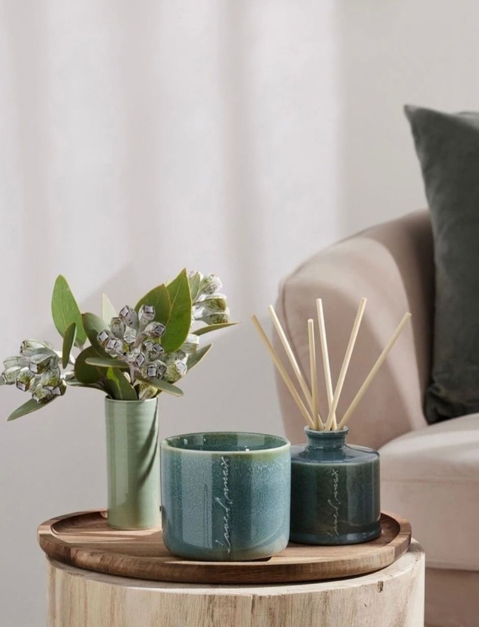 Stylish tray with green candles and dried flowers on a coffee table beside a sofa