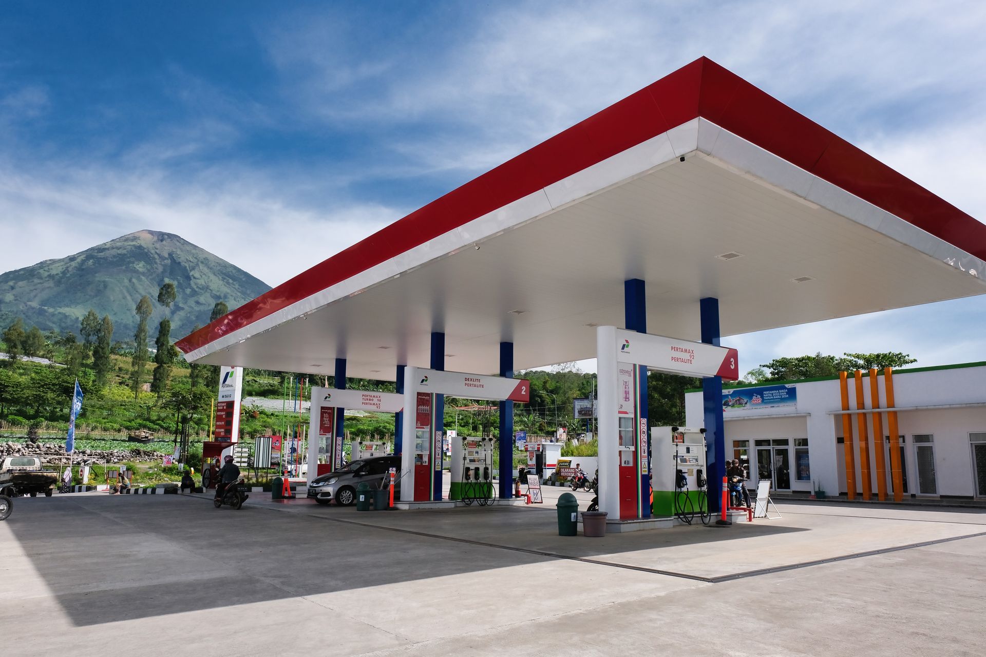 Gas station with red-and-white canopy in front of a mountain backdrop