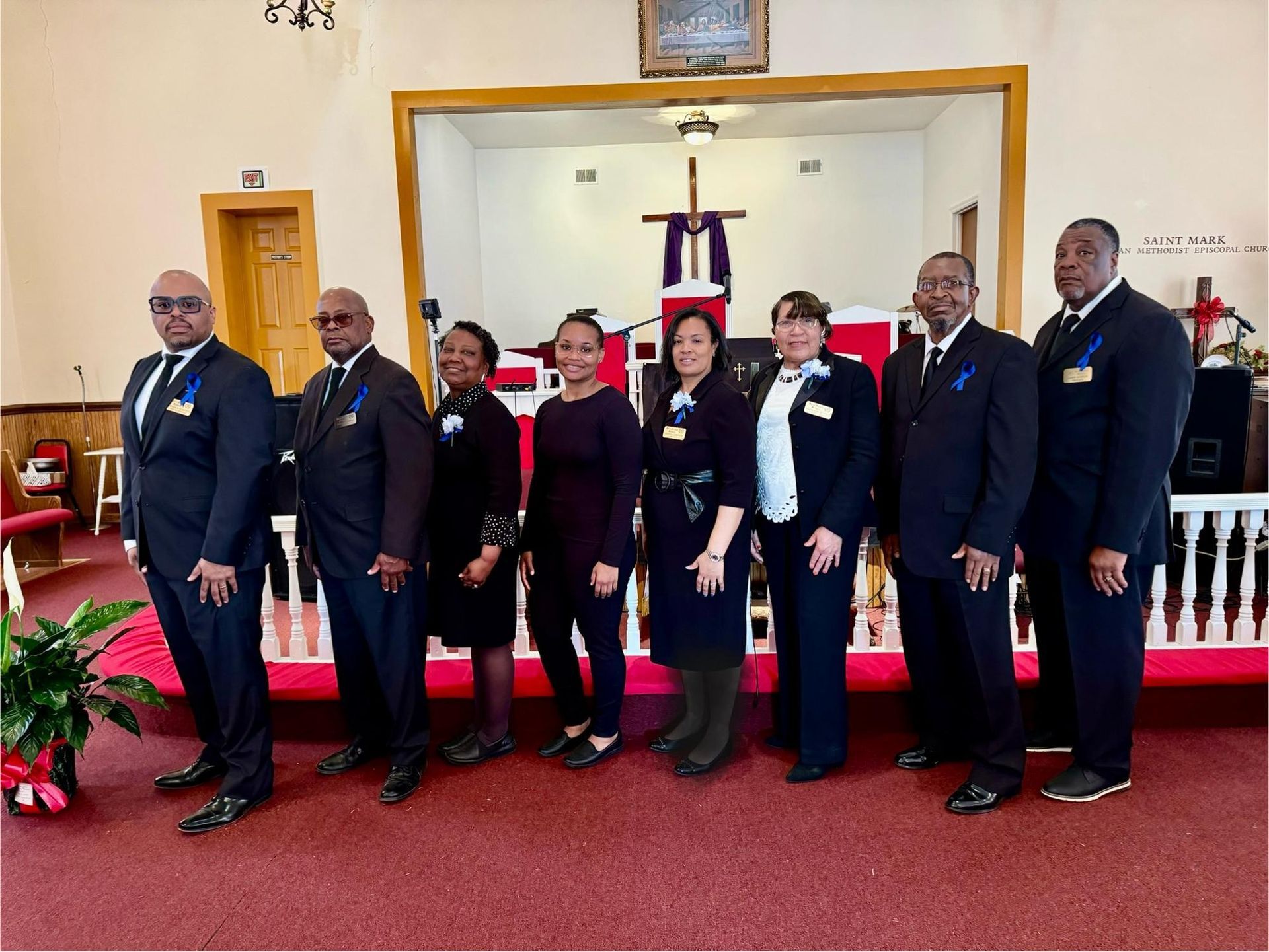 Group of people in black suits and dresses standing inside a church.