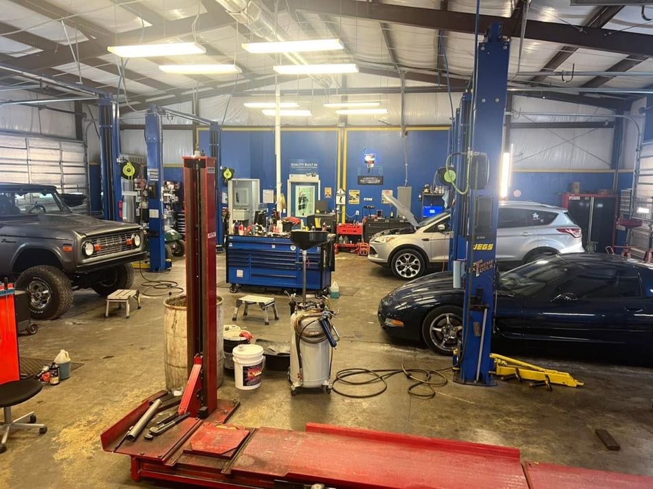 Auto repair shop with cars on lifts and tools scattered across the garage floor