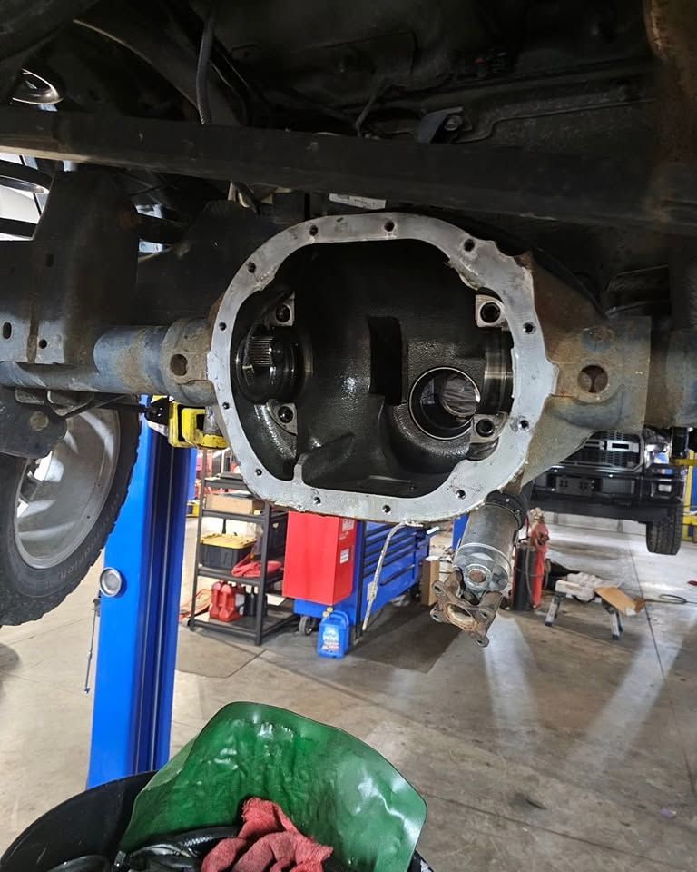 Car lifted in a garage, showing the exposed rear differential housing and undercarriage.