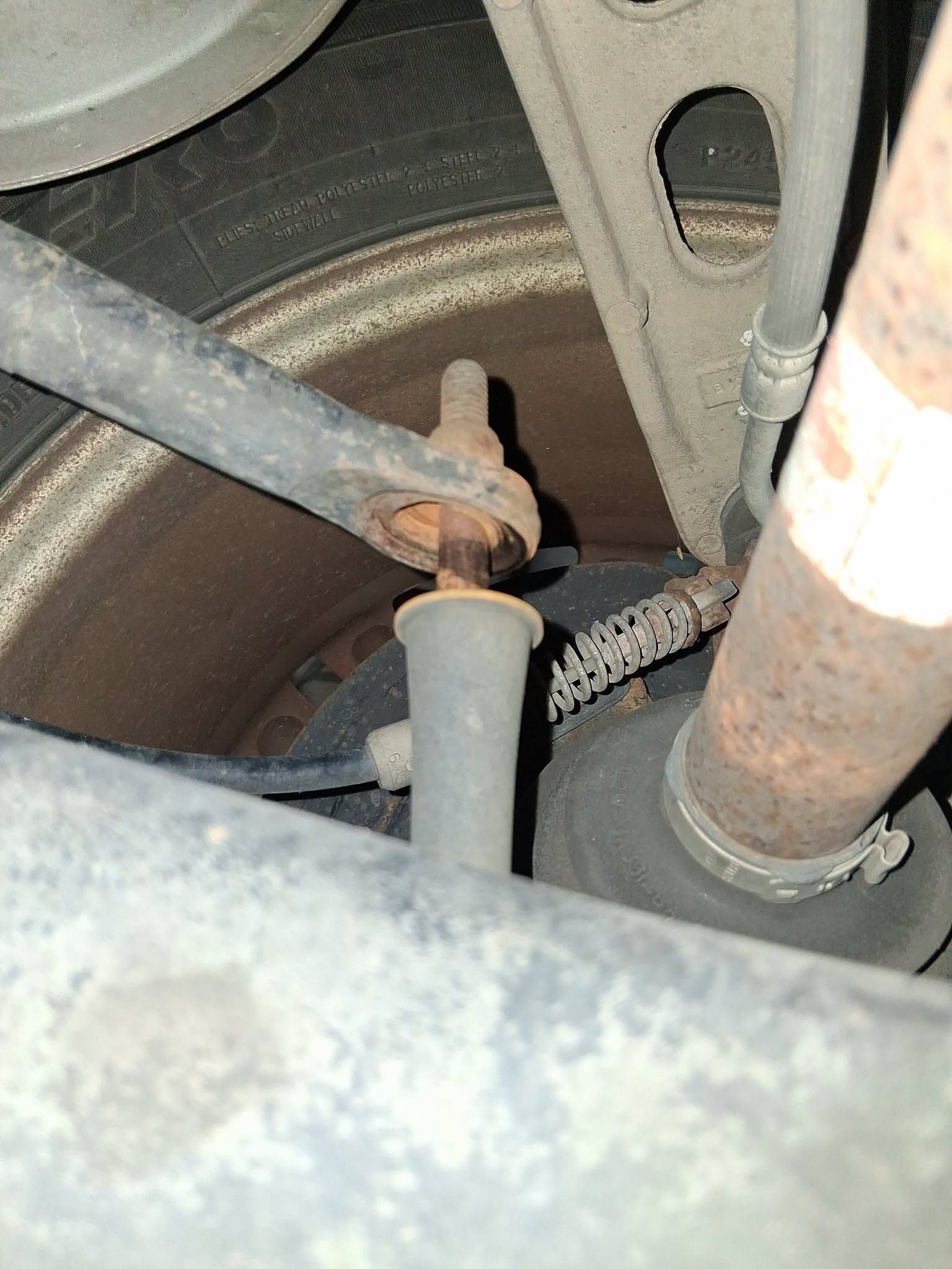 Close-up of a rusty car suspension and wheel assembly near the brake rotor.