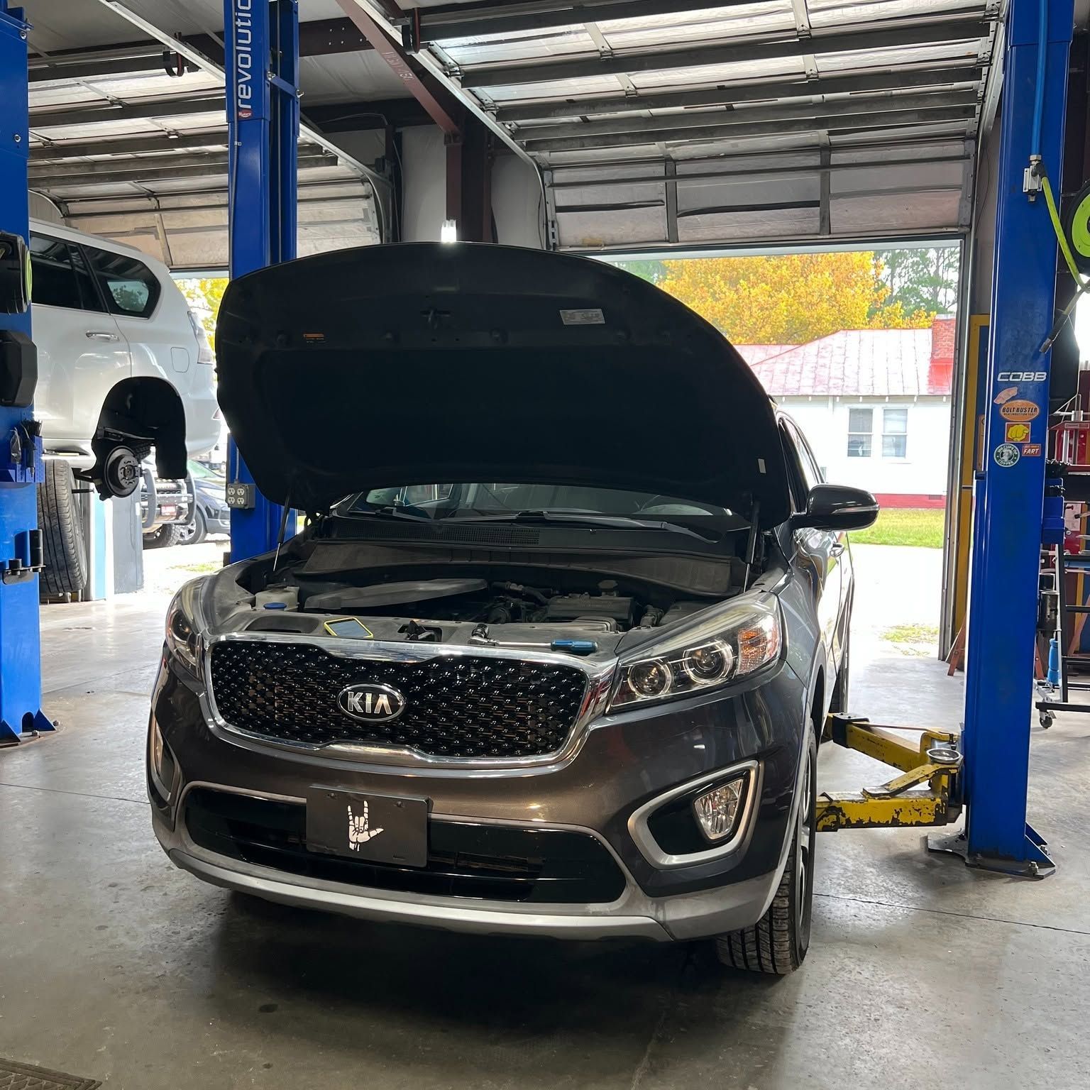 Black SUV in an auto shop with its hood open on a lift bay