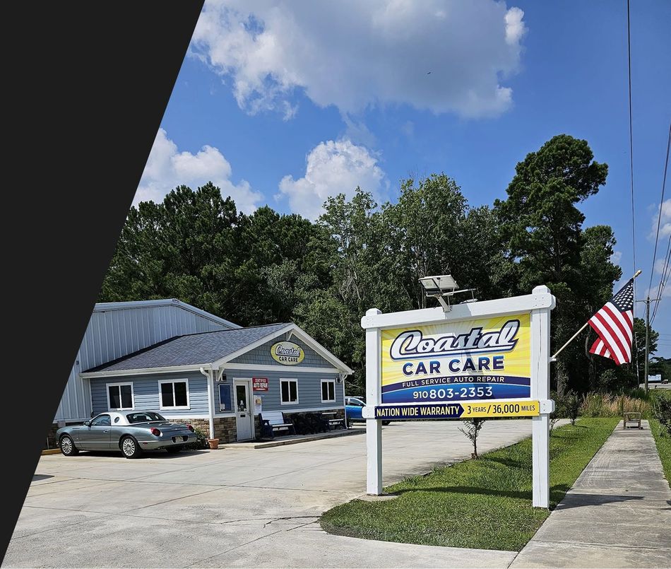 Auto repair shop with blue building, sign, parked car, and American flag under a sunny sky