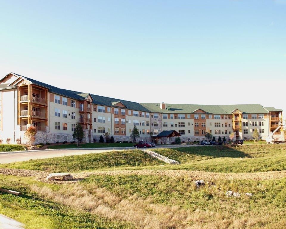 A large building with a green roof sits in the middle of a grassy field