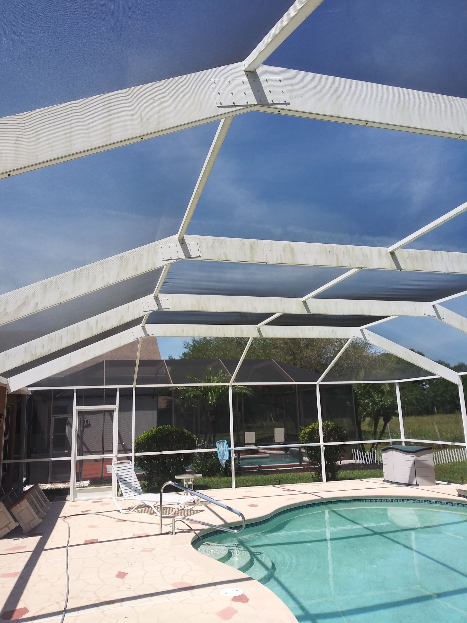 A screened in swimming pool with a blue sky in the background