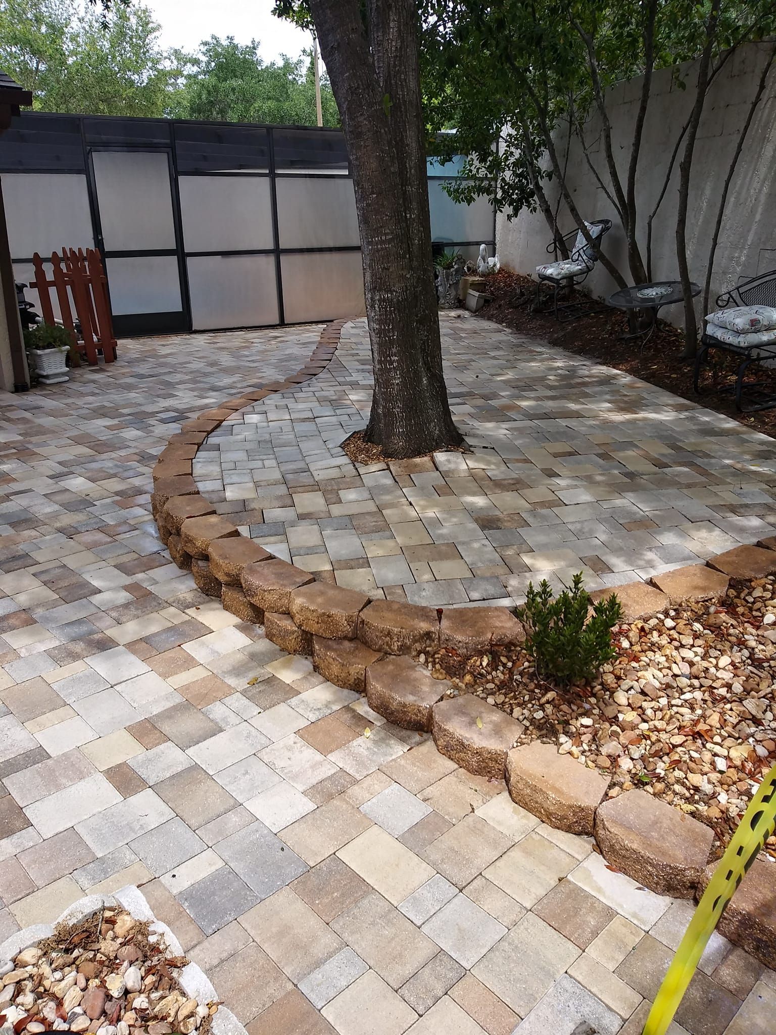A brick patio with a tree in the middle of it.