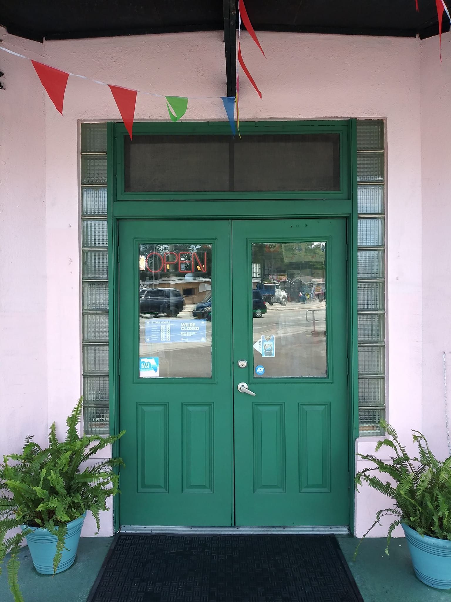 A pink building with a green door and potted plants
