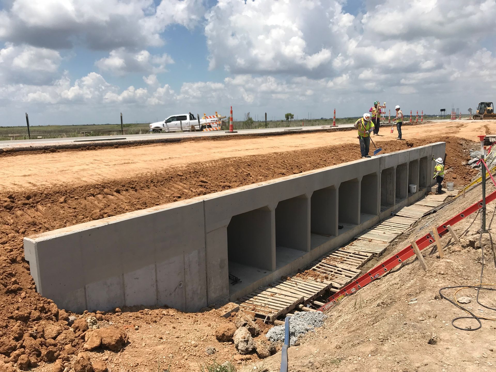 a large concrete structure is being built on the side of a dirt road .