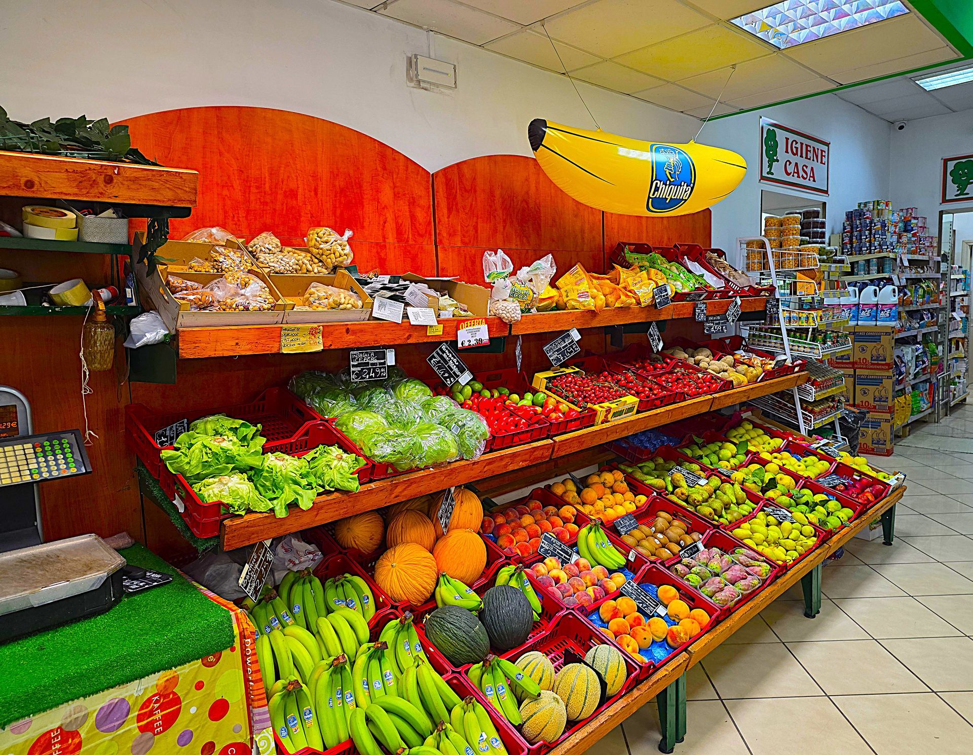 Banco di frutta e verdura ricco di colori, tra cui banane, arance, mele e verdure a foglia verde.