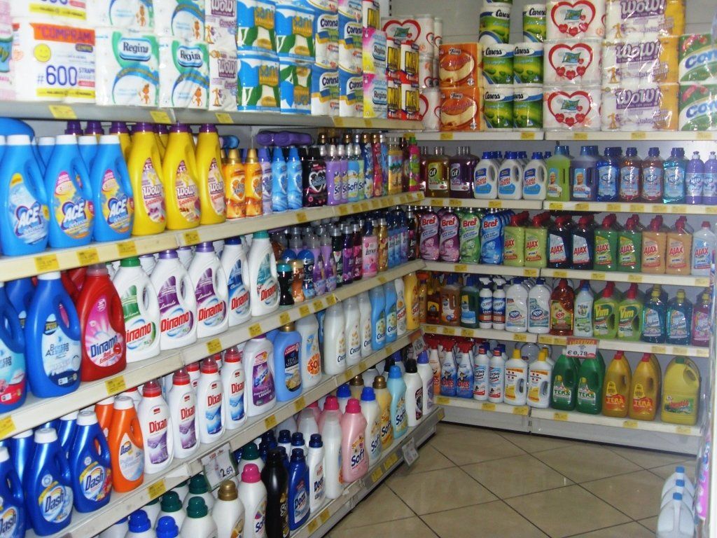 Un corridoio di un supermercato pieno di coloratissimi prodotti per la pulizia, detersivi e articoli per la casa sugli scaffali.