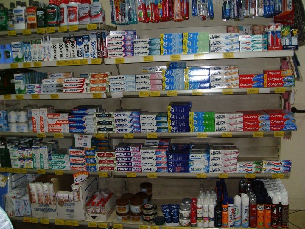 Scaffali pieni di medicinali e articoli da toeletta assortiti in una piccola corsia del negozio.