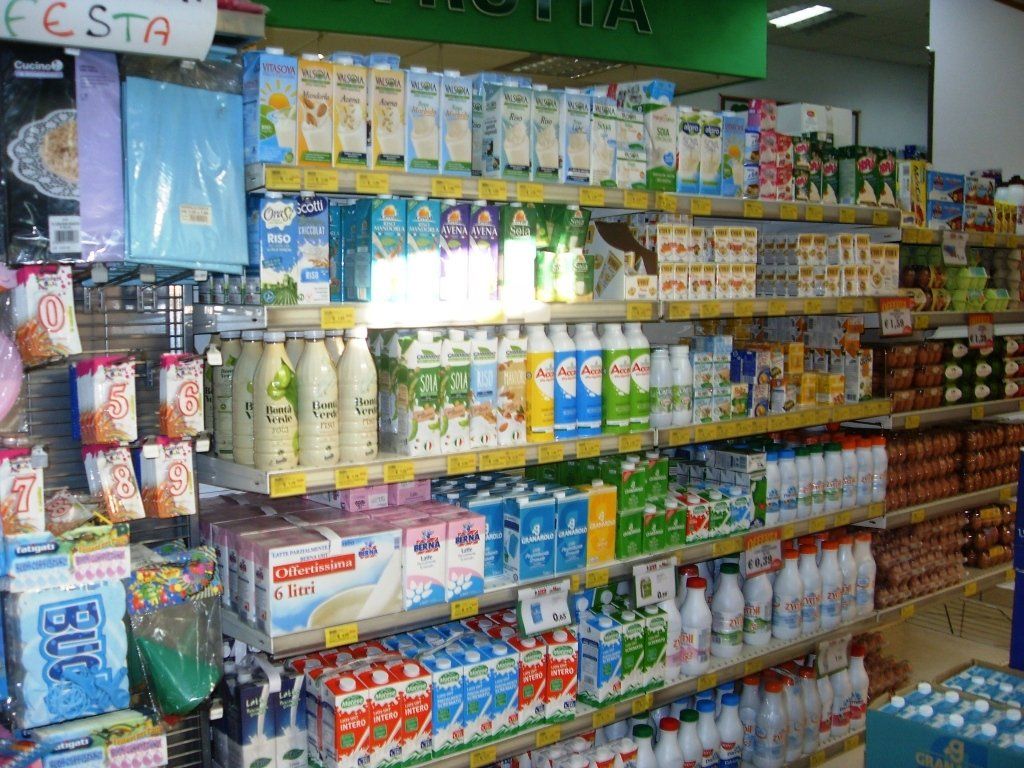 Scaffali pieni di colorati prodotti per la casa e per la pulizia in una piccola corsia di un supermercato.