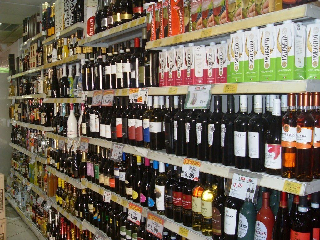 Corridoio del vino di un supermercato con file di vini rossi, bianchi e in cartone sugli scaffali