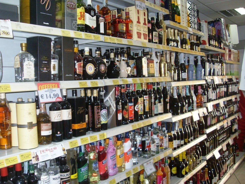 Uno scaffale di un'enoteca pieno di bottiglie di liquore assortite con i relativi cartellini del prezzo.