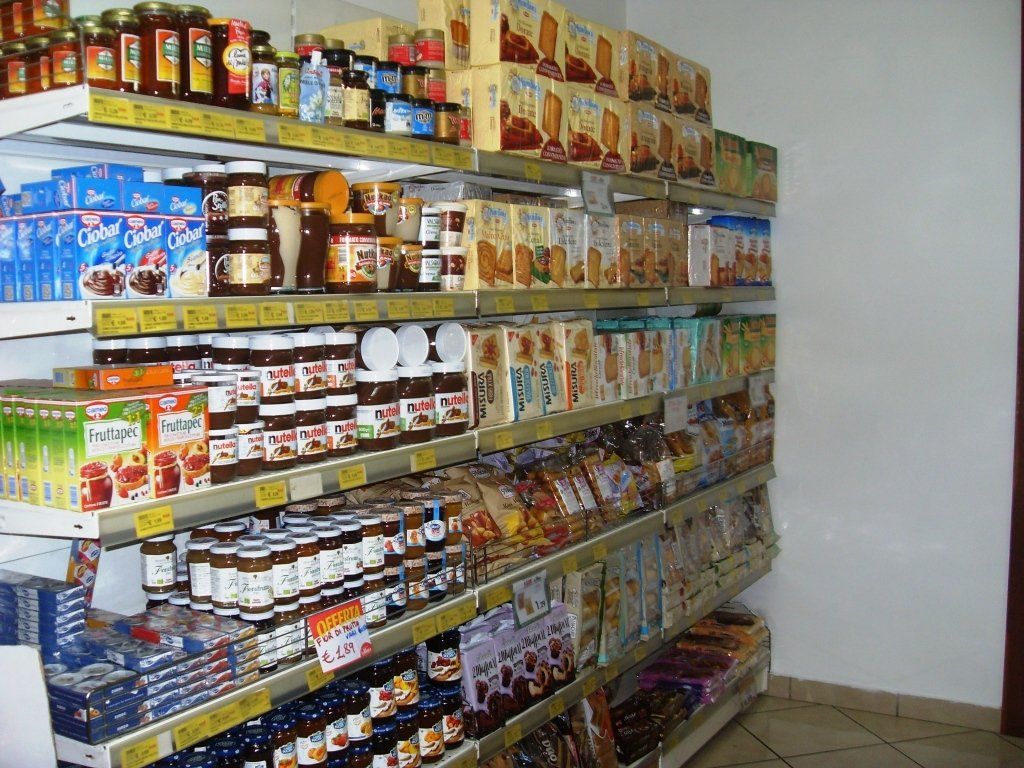 Scaffali pieni di vari prodotti alimentari confezionati in una piccola corsia di un negozio di alimentari.