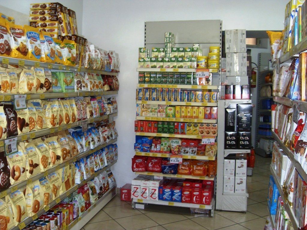 Una corsia stretta di un supermercato, con scaffali di snack e bevande confezionate su entrambi i lati.