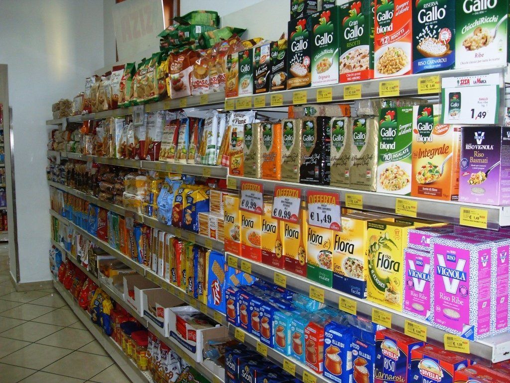 Un corridoio di un negozio fiancheggiato da colorate scatole di cereali e prodotti alimentari confezionati sugli scaffali.