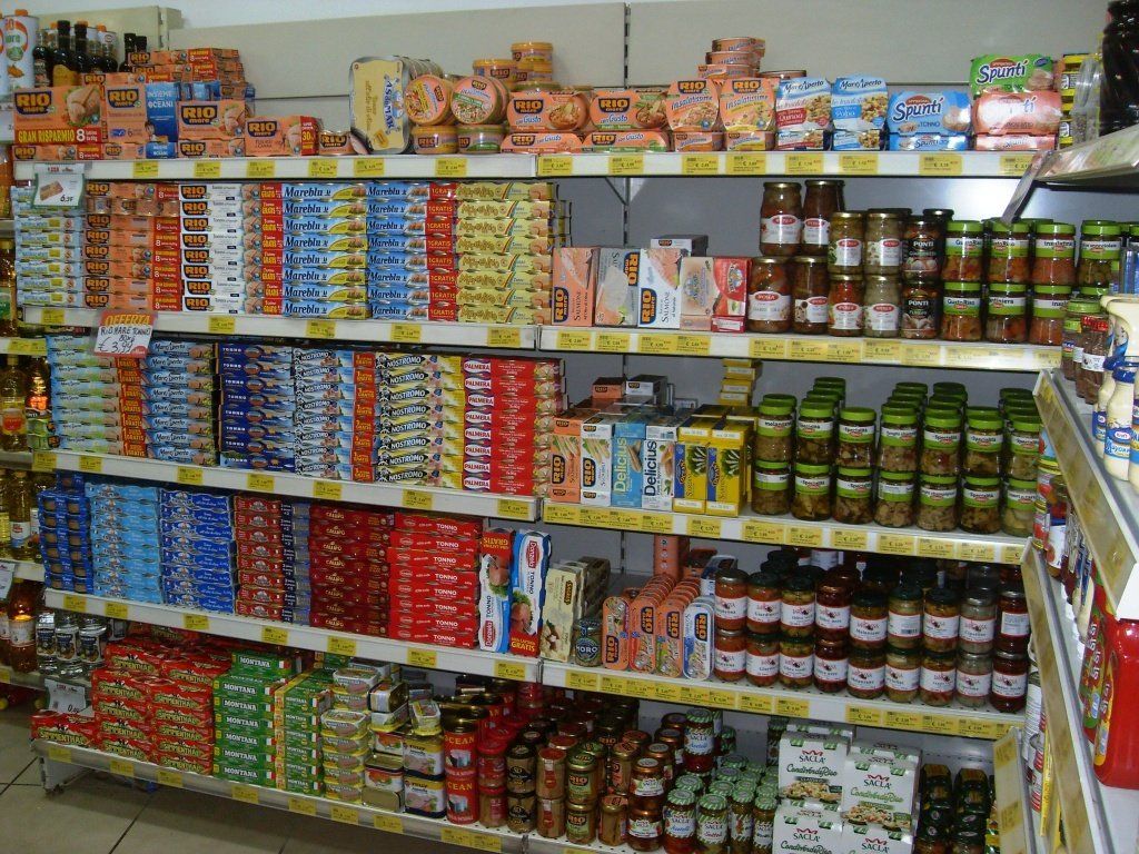 Gli scaffali del supermercato sono pieni di alimenti assortiti in scatola, confezionati e in barattolo.