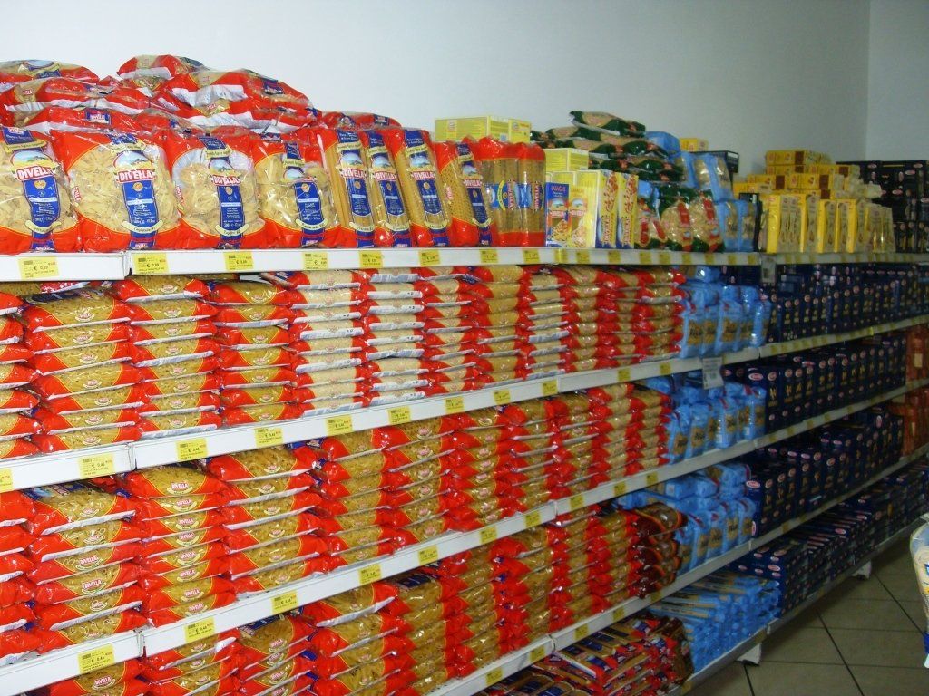 Un corridoio di un supermercato è pieno di snack e noodles confezionati e colorati sugli scaffali.