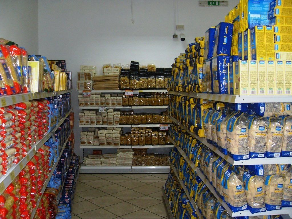 Una corsia di supermercato piena di scaffali con prodotti confezionati e bottiglie su entrambi i lati.