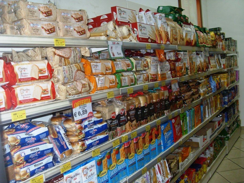 Corridoio del negozio pieno di snack e bevande confezionati disposti su lunghi scaffali