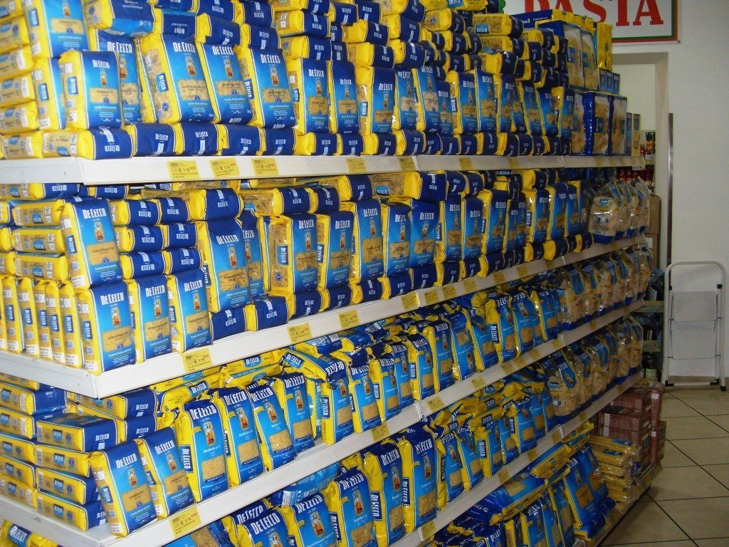 Scaffali pieni di sacchetti blu e gialli contenenti prodotti confezionati in una corsia di un negozio.