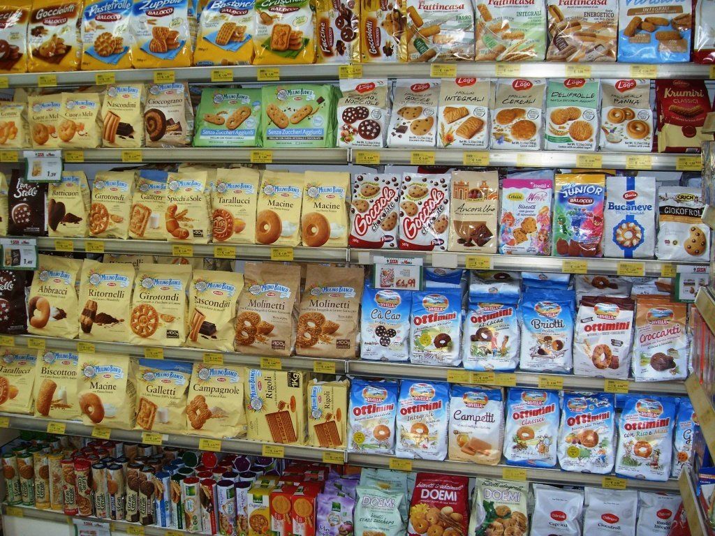 Lo scaffale del negozio è pieno di coloratissime confezioni di cereali per la colazione e snack.